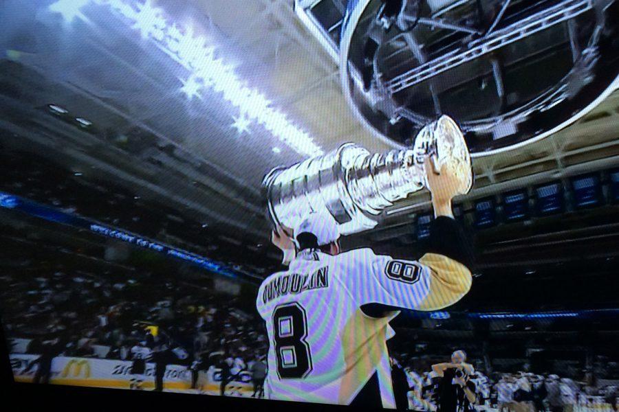 Brian Dumoulin hoists the Stanley Cup after his team, the Pittsburgh Penguins, wins the Stanley Cup Finals.